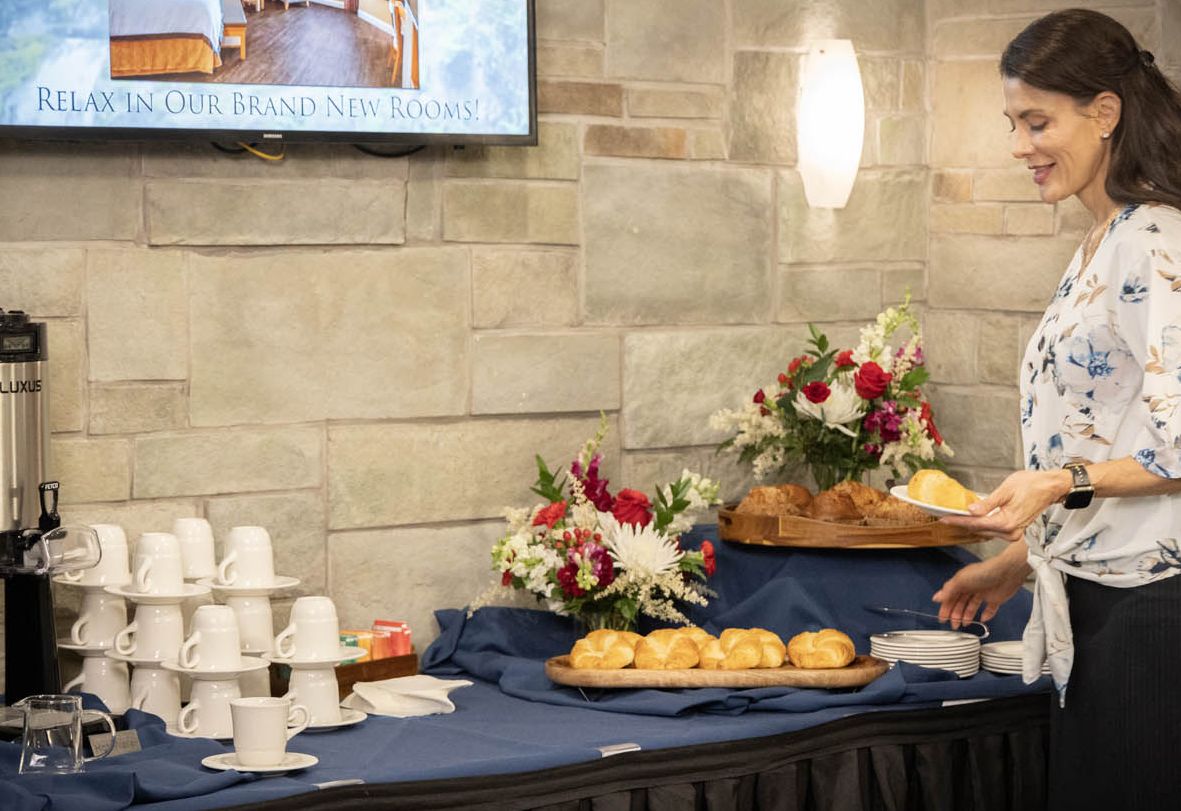 A woman selects some breads and coffee at a break table