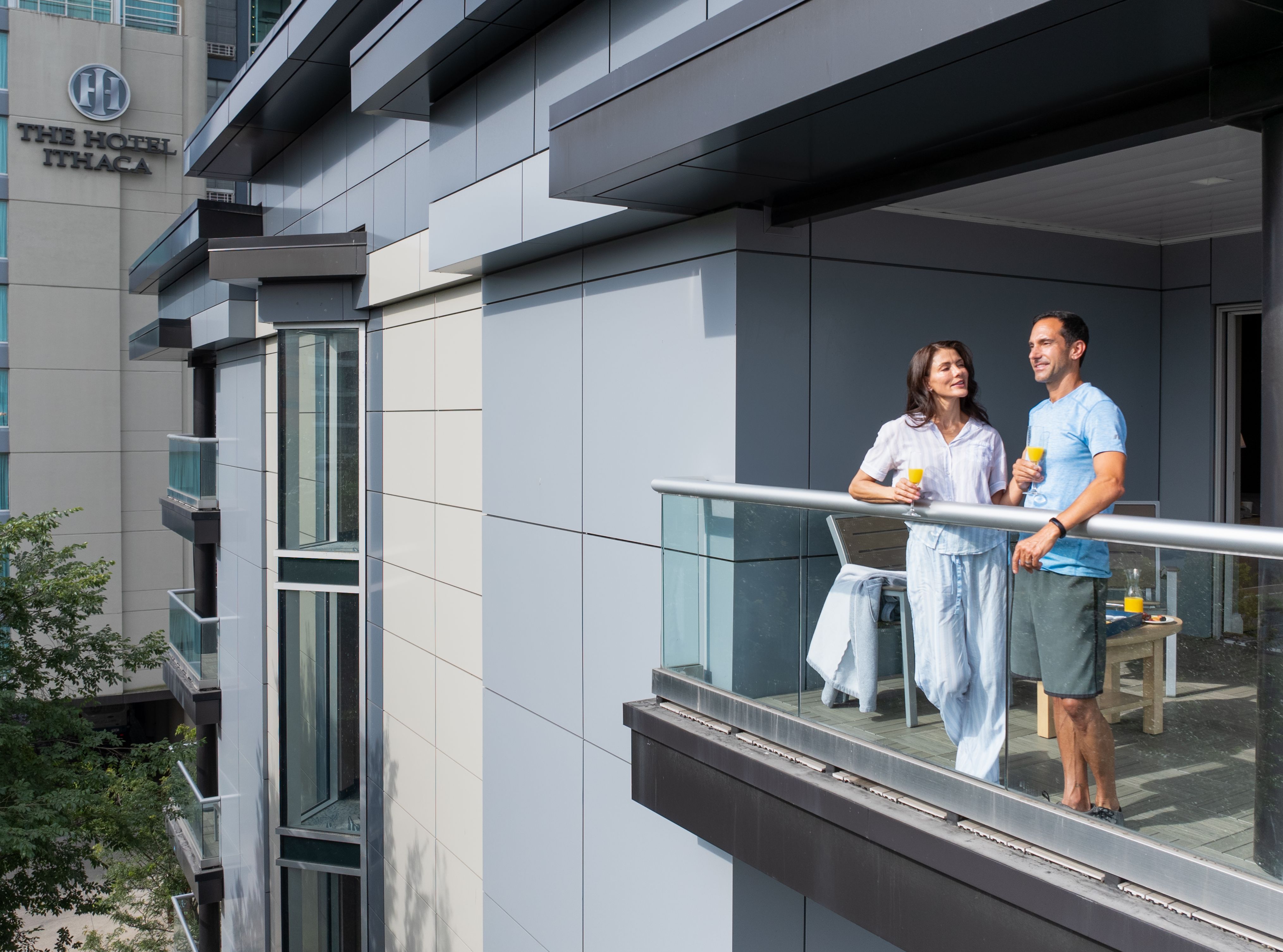 A couple stands looking out from their balcony at The Hotel Ithaca