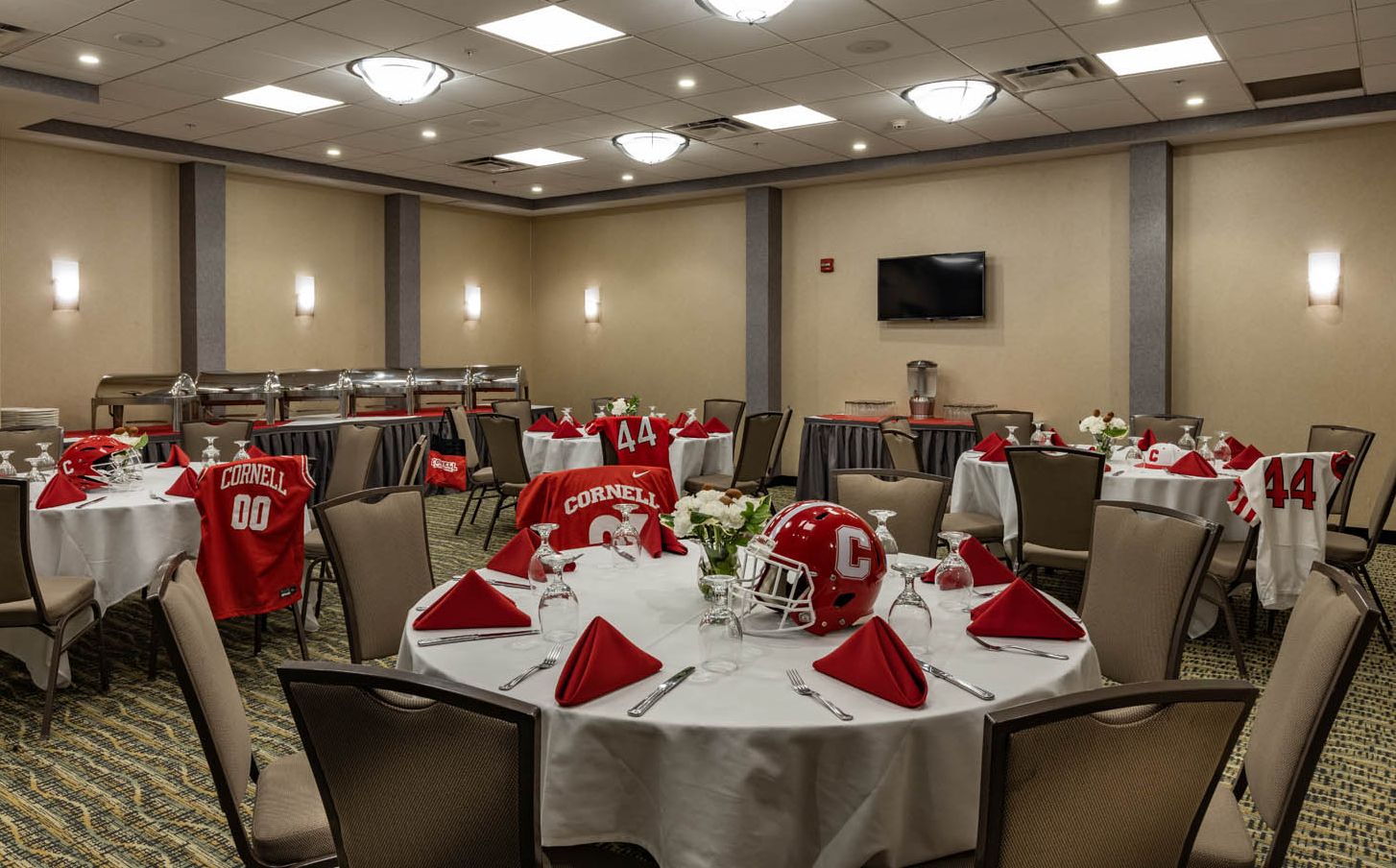 A meeting room with food service trays set up and Cornell University sports memorabilia on each table